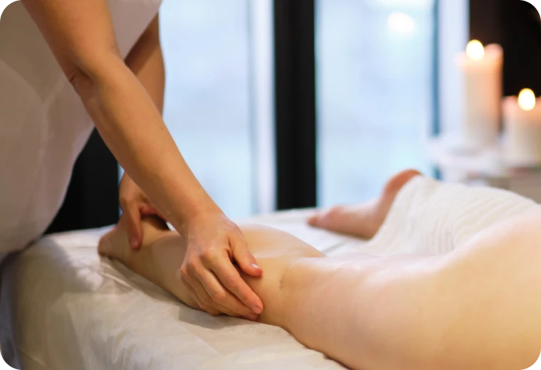 Praticienne réalisant un massage drainant sur la jambe pour soulager la sensation de jambes lourdes